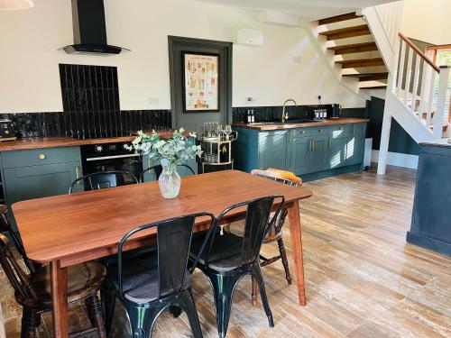 a kitchen with a wooden table with chairs and a vase of flowers at Rayners Farm Lodge in Mattishall