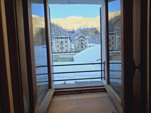 an open window with a view of a snowy city at Grand Hotel Ceresole Reale Bill Apartment in Ceresole Reale