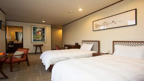 a hotel room with two beds and a table at Harriway Hotel Hakone in Hakone