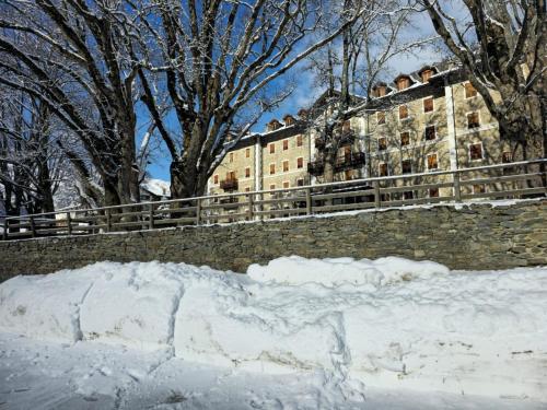 a building in the snow next to a stone wall at Grand Hotel Ceresole Reale Bill Apartment in Ceresole Reale