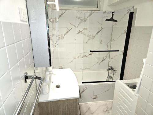 une salle de bain blanche avec un lavabo et une douche dans l'établissement Studio entre plages et Monaco climatisé parking, à Roquebrune-Cap-Martin