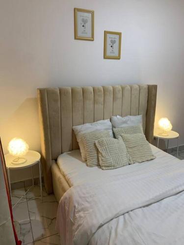 a bed with pillows and two tables with lamps at Le bien être in Libreville