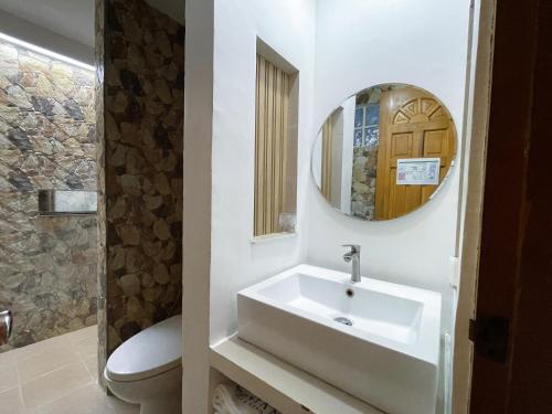 a bathroom with a sink and a toilet and a mirror at Montani Beach Resort Puerto Galera powered by Cocotel in Puerto Galera