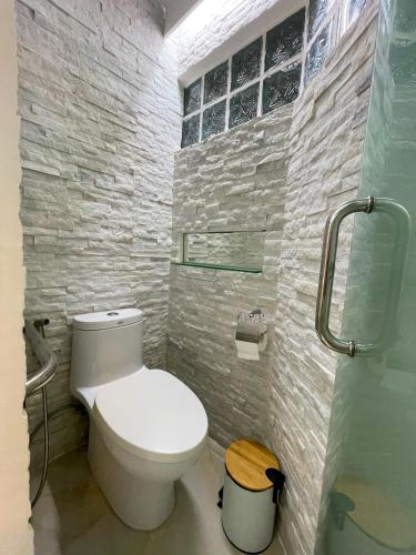a bathroom with a white toilet and a stone wall at Montani Beach Resort Puerto Galera powered by Cocotel in Puerto Galera