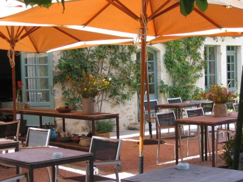 een groep tafels en stoelen met een paraplu bij Les Deux Ponts in Pierre-Perthuis