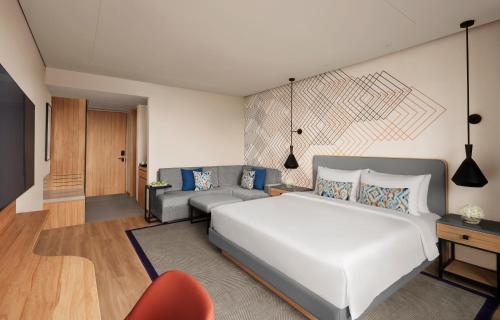 a bedroom with a large white bed and a couch at Hyatt Place Vadodara in Vadodara