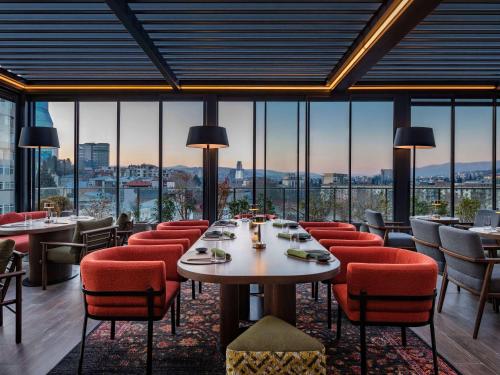 - un restaurant avec des tables, des chaises et de grandes fenêtres dans l'établissement Swissôtel Tbilisi, à Tbilissi