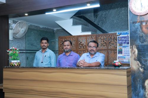 Drei Männer standen hinter einer Theke in einem Restaurant in der Unterkunft MR.WHITE PRIME RESIDENCY in Chennai