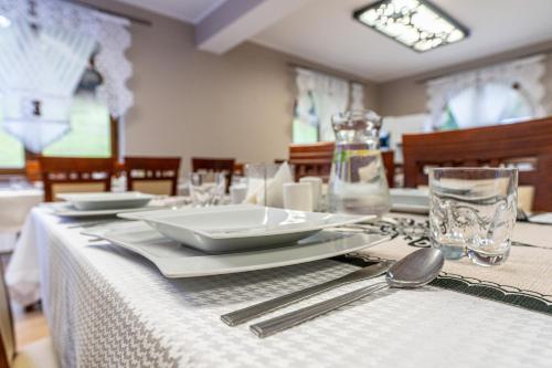 a table with a white table cloth and plates and silverware at Leśny Dworek Biały Dunajec in Zakopane