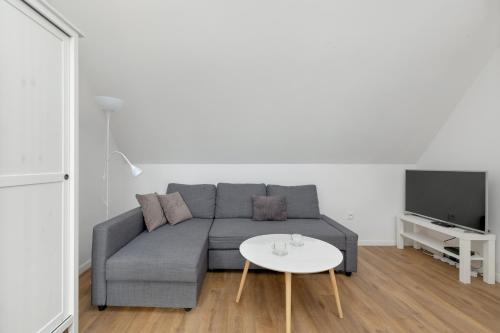ein Wohnzimmer mit einem grauen Sofa und einem weißen Tisch in der Unterkunft Unique Apartments in Szczecin by Rent like home in Stettin