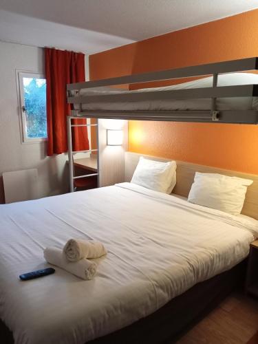 a bedroom with a bed with two towels on it at Premiere Classe Saint Brice Sous Foret in Saint-Brice-sous-For&ecirc;t
