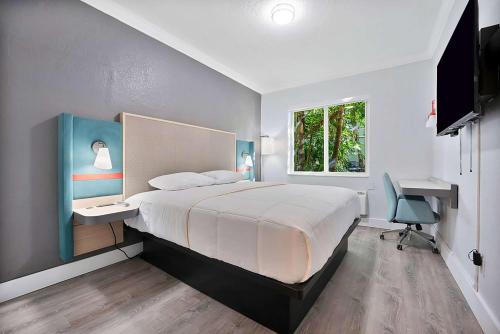 a bedroom with a bed and a desk and a window at Garden Hotel Miami Airport, Trademark Collection by Wyndham in Miami
