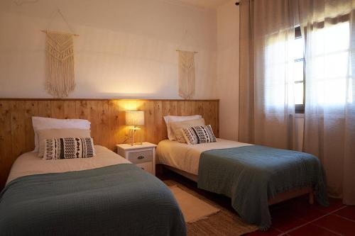two beds sitting in a room with a window at Quinta do Marmeleiro - Casa Marmeleiro in Santiago do Cacém