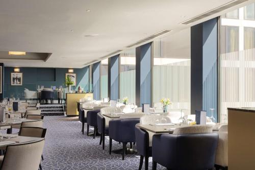 a dining room with tables and chairs and windows at Hilton London Gatwick Airport in Horley