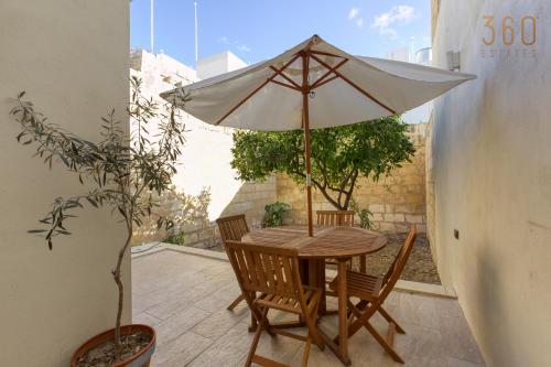a table and chairs with an umbrella on a patio at Stylish 3BR townhouse with Private Terrace & BBQ by 360 Estates in Paola