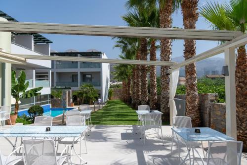 een patio met tafels en stoelen en palmbomen bij Angela Studios Apartments in Sissi