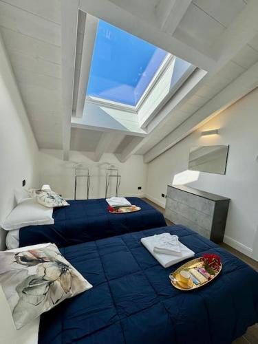 una camera con due letti con lenzuola blu e una finestra di Apt. Aries - Penthouse Menaggio a Menaggio