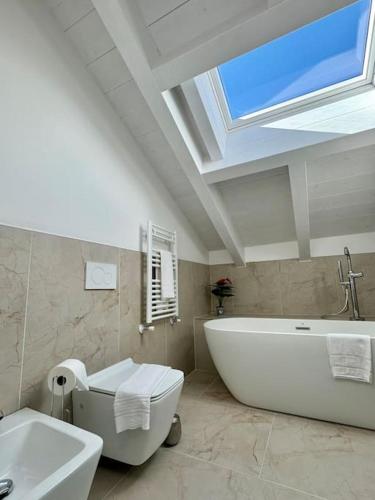 un bagno con una grande vasca bianca e una finestra di Apt. Aries - Penthouse Menaggio a Menaggio