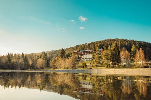 a house on a hill next to a lake at Hotel Partizán in Tale