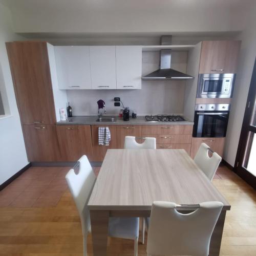 a kitchen with a wooden table and white chairs at Casa Reggio Emilia in Reggio Emilia