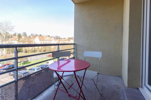 d'une table et d'une chaise rouges sur un balcon avec vue. dans l'établissement Le Mangin, à Saint-Avold