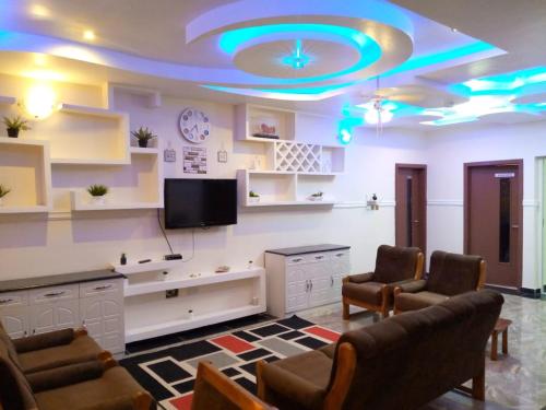 SANAMOND VILLA في Dodowa: غرفة معيشة مع تلفزيون بشاشة مسطحة وكراسي