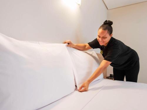 a woman painting a white wall in a room at ibis Styles Goiânia Shopping Estação in Goiânia