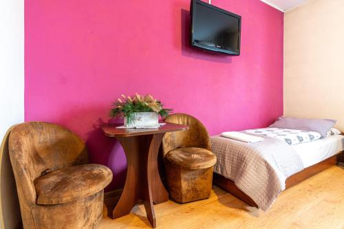 a bedroom with a pink wall and a table and chairs at Leśny Dworek Biały Dunajec in Zakopane