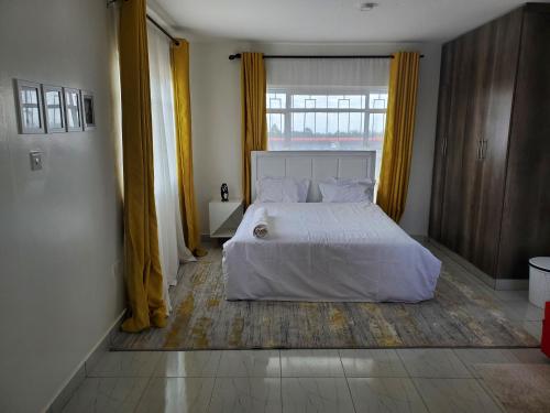 een slaapkamer met een wit bed en een raam bij Luxury penthouse in Nairobi