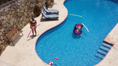 a man in a swimsuit standing next to a swimming pool at Villa Costa Chica Comodisimo piscina gigante jardines in Acapulco