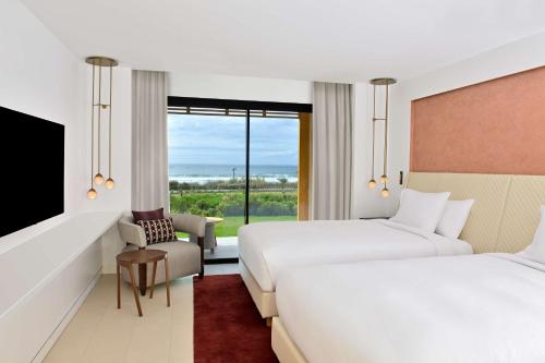 a hotel room with two beds and a window at Hilton Taghazout Bay Beach Resort & Spa in Taghazout