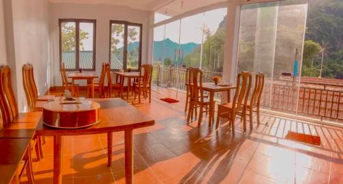 Un comedor con mesas y sillas y un balcón. en An Huy Homestay Mai Châu, en Mai Chau
