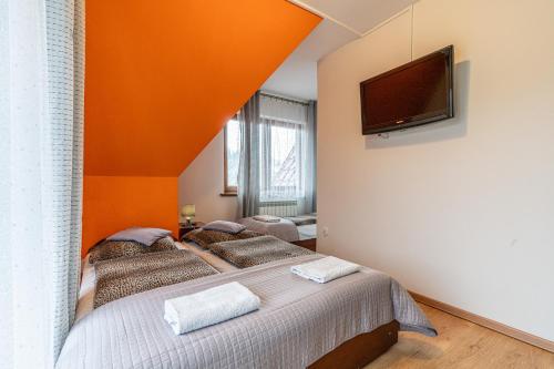 a bedroom with two beds and a flat screen tv at Leśny Dworek Biały Dunajec in Zakopane