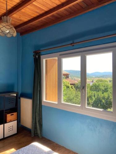Cette chambre dispose de deux fenêtres et d'un mur bleu. dans l'établissement La Villa Tranquille aux portes des Cévennes, à Brissac