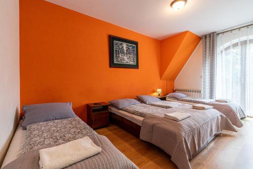 two beds in a room with orange walls at Leśny Dworek Biały Dunajec in Zakopane