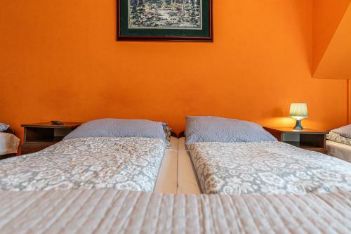 two beds in a bedroom with an orange wall at Leśny Dworek Biały Dunajec in Zakopane