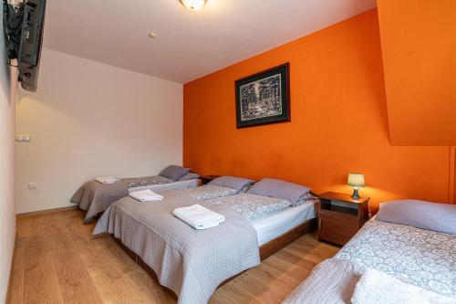 three beds in a room with orange walls at Leśny Dworek Biały Dunajec in Zakopane