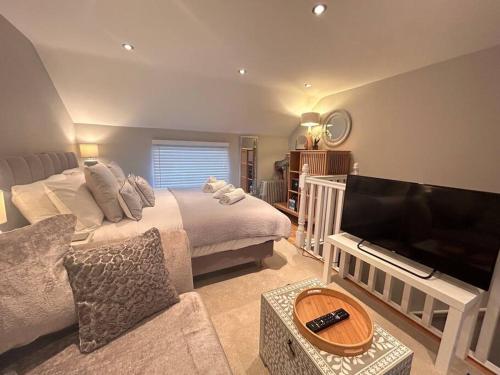 a bedroom with a bed and a flat screen tv at The Gatehouse, Bijou studio apartment - sleeps 2 in Easingwold