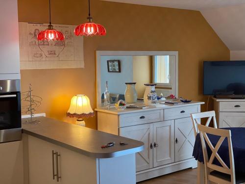 une cuisine avec des armoires blanches et une télévision à écran plat dans l'établissement Le St André Conciergerie Leroy, à Le Portel