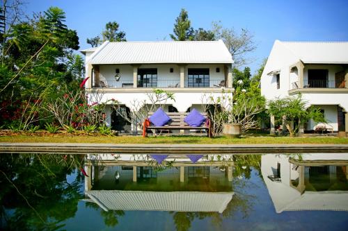 a house with two chairs sitting next to a body of water at Isla's Ridge - A CGH Earth SAHA Experience in Kodaikānāl