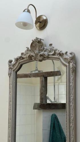 - un miroir dans la salle de bains avec une lumière et une serviette verte dans l'établissement Très jolie maison de village, à Lourmarin