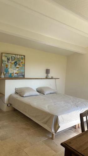 une chambre avec un lit avec un tableau sur le mur dans l'établissement Très jolie maison de village, à Lourmarin