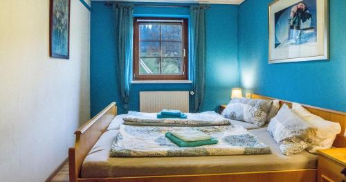 a bedroom with a bed with blue walls and a window at Oberengenbachhof in Eisenbach