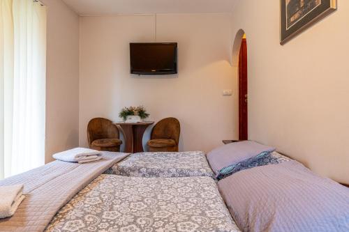 two beds in a room with a tv on the wall at Leśny Dworek Biały Dunajec in Zakopane