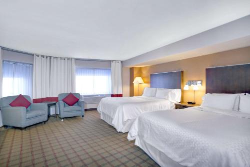 une chambre d'hôtel avec deux lits et deux chaises dans l'établissement Wyndham Fallsview Hotel, à Niagara Falls