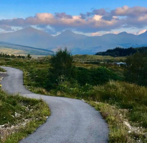 a winding road in the middle of a field at Cosy Highland Cottage Tyndrum centrally located in Tyndrum