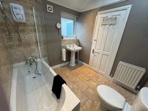 a bathroom with a tub and a toilet and a sink at Ennerdale Edge - 4 Bed House in Cleator Moor