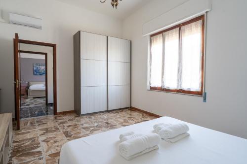 una camera da letto bianca con due asciugamani su un letto di Spacious House in Sinis a Càbras