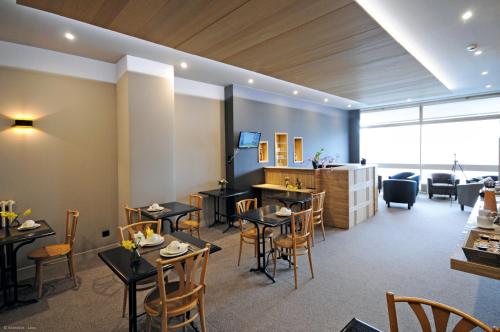 a restaurant with tables and chairs in a room at Cit'Hotel De Harlay in Compiègne