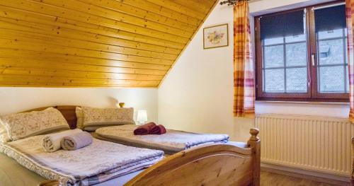 two beds in a room with a wooden ceiling at Oberengenbachhof in Eisenbach